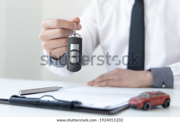 Car dealers or insurance managers cover and\
protect against damage and the risk of driving, Hold the car keys,\
Protecting and after-sales care\
concept.