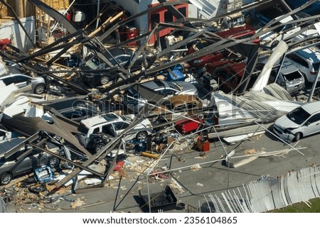 Car dealership building destroyed by hurricane with damaged cars under ruins in Florida. Natural disaster and its consequences