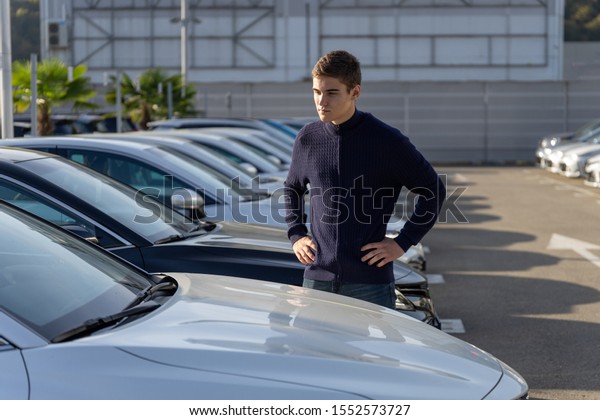 Car dealership customer chooses the\
car. A row of new cars parked at a car dealership\
stock