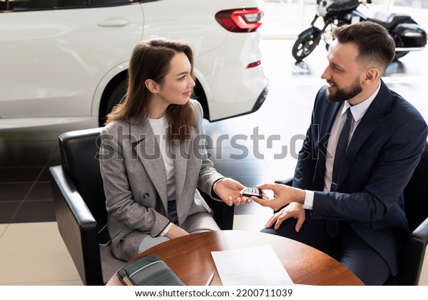 car dealership manager handing\
over keys to new car buyer. the concept of buying a car on\
lease