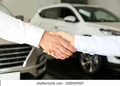 Car Dealership Sales Person At Work Concept. Portrait Of Young Sales Representative Wearing Formal Wear Suit, Showing Vehicles At Automobile Exhibit Center. Close Up, Copy Space, Background.