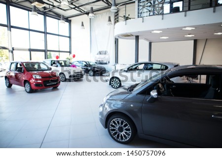 Car dealership showroom interior with brand new vehicles for sale.