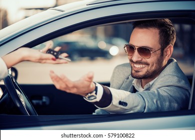Car dealership.Young man receiving car key from saleswoman.