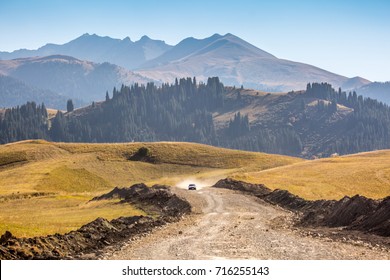 A Car In The Desert Quickly Rides Through The Mud With Clouds Of Dust From Under The Wheels, Against The Backdrop Of The Mountains. Dakar Rally. SUV Rides Off The Road