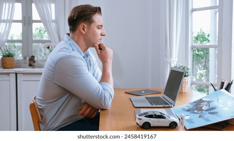 Car design engineer working on car prototype for automobile business at home office. Automotive engineering designer carefully analyze, finding flaws and improvement for car design. Synchronos