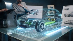 Ingenieure Von Automobil-Designern, Die Holografische App In Digitalen Tablets Verwenden. Entwicklung Eines Modernen, Innovativen Und Hochmodernen, Umweltfreundlichen Elektroautos Mit Nachhaltigen Standards. Sie Testen Die Aerodynamischen Eigenschaften