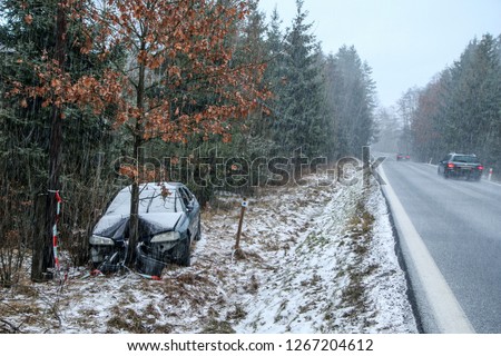 Car destroyed during the traffic accident. It was caused by the bad weather conditions in winter, because of the black ice or snow. The car is abandoned and stands by the road in the snowfall.