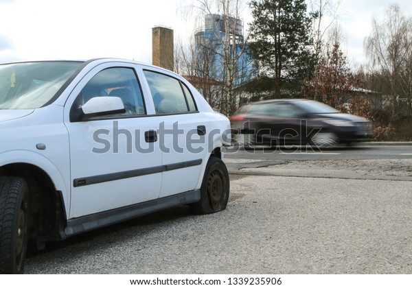 A car\
destroyed during the traffic accident. The car is abandoned and\
stands by the road. It is passed by other cars.\
