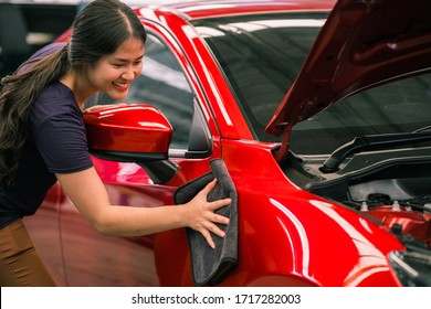 Car detailing - Asian woman holds the microfiber in hand and polishes the car. woman cleaning car with microfiber cloth - Powered by Shutterstock