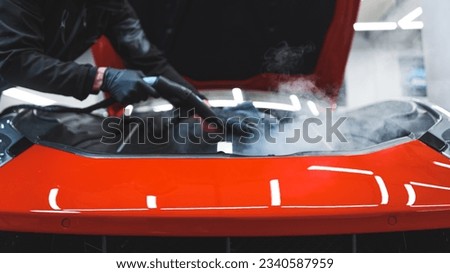car detailing concept, cleaning a car with a cloth and steam, indoors. High quality photo