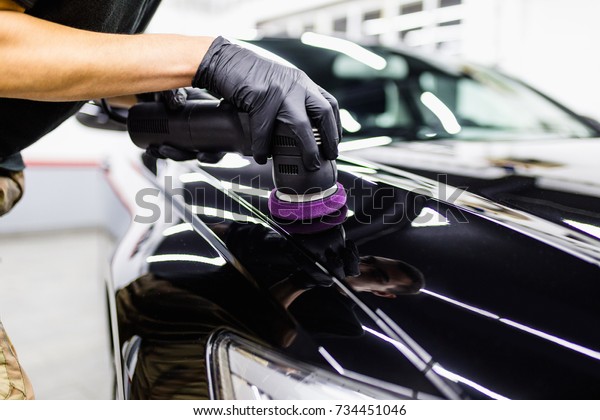 Car detailing - Hand with orbital polisher in auto\
repair shop. 