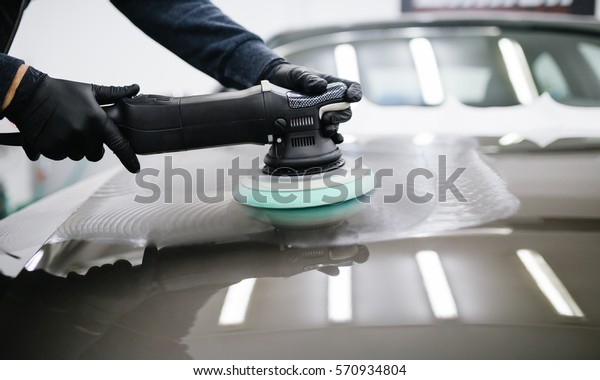 Car detailing - Hands with orbital\
polisher in auto repair shop. Selective\
focus.