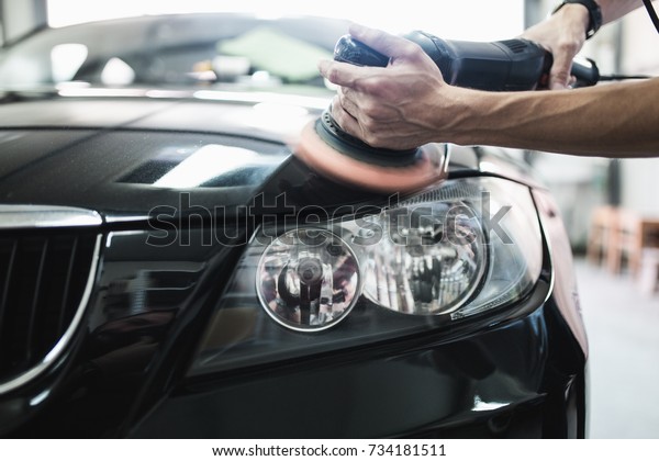 Car detailing - Hands with orbital\
polisher in auto repair shop. Selective\
focus.\
