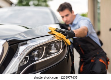 Car detailing - the man holds the microfiber in hand and polishes the car. Selective focus. - Shutterstock ID 1233977635