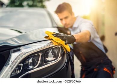 Car detailing - the man holds the microfiber in hand and polishes the car. Selective focus. - Shutterstock ID 682966966