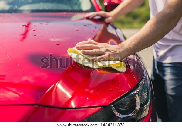 Car detailing - the man holds the microfiber in
hand and polishes the car. Selective focus. Car detailing series :
Worker cleaning red car. 