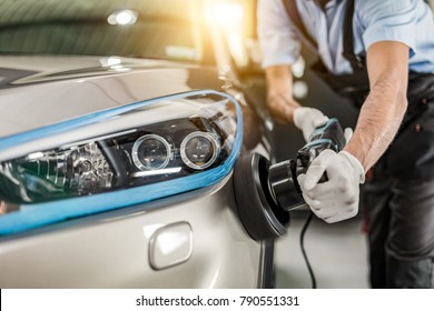 Car detailing - Man holds a polisher in the hand and polishes the car. Selective focus.