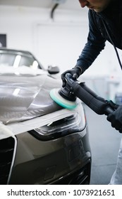 Car detailing - Man with orbital polisher in repair shop polishing car. Selective focus.
