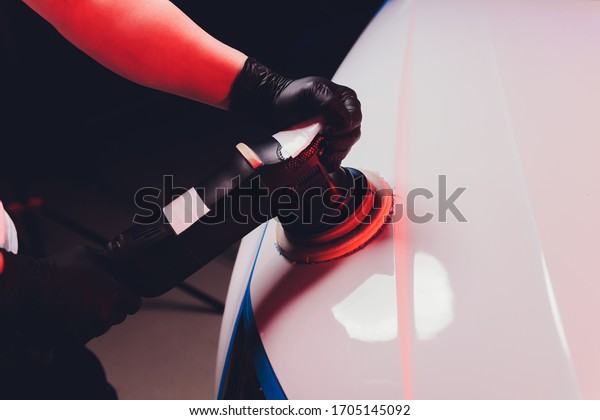Car detailing - Man with orbital\
polisher in repair shop polishing car. Selective\
focus.