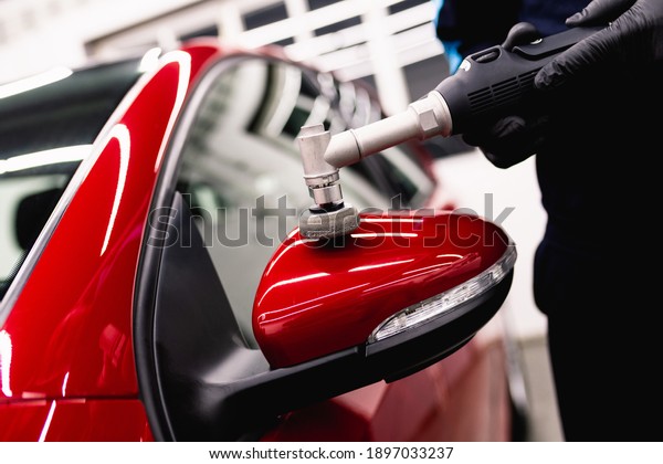 Car detailing - Man with orbital\
polisher in repair shop polishing car. Selective focus.\

