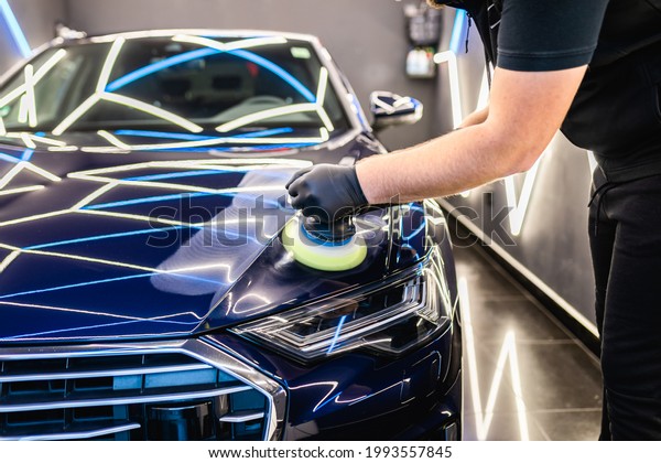 Car detailing - Man with orbital\
polisher in repair shop polishing car. Selective\
focus.	