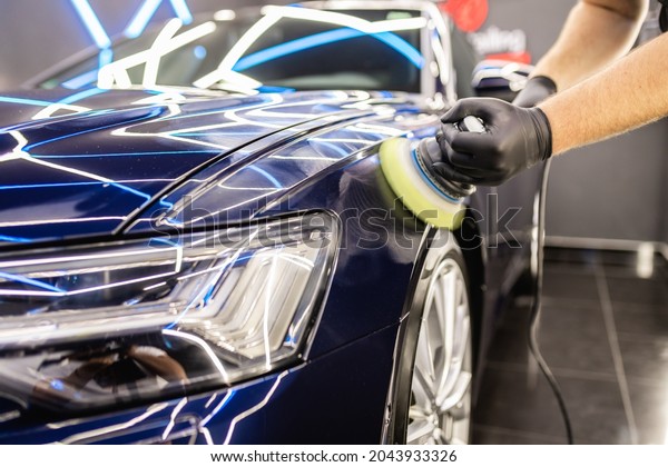 Car detailing - Man with orbital\
polisher in repair shop polishing car. Selective\
focus.	