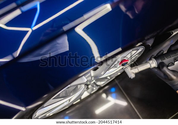Car detailing - Man with orbital
polisher in repair shop polishing car. Selective
focus.	