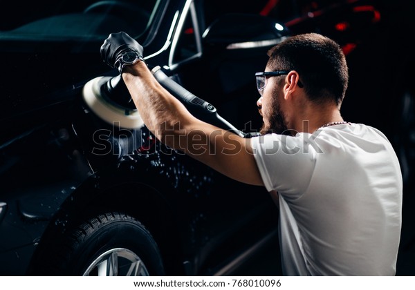 Car detailing - man with orbital\
polisher in auto repair shop. Selective\
focus.