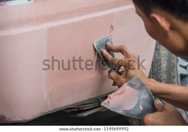 Car Detailing - Man working in auto repair shop,\
polishing and preparing auto parts for coloring. Focus on the human\
hand.