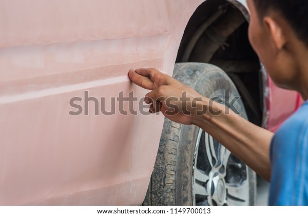 Car Detailing - Man working in auto repair shop,
polishing and preparing auto parts for coloring. Focus on the human
hand.