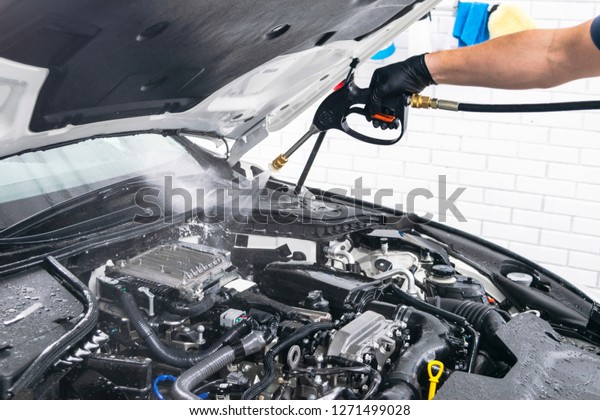 Car detailing.\
Manual car wash engine with pressure water. Washing car engine with\
water nozzle. Carwash worker cleaning vehicle engine. Man spraying\
pressure washer for car\
wash.