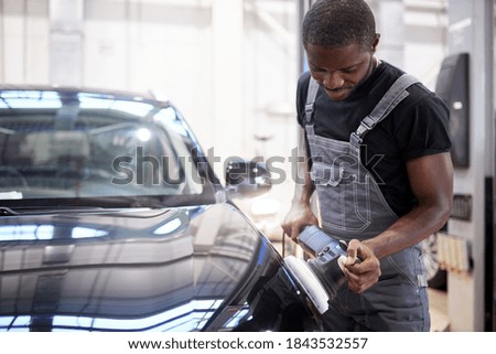 car detailing and polishing concept. young african professional car service male worker, auto mechanic with orbital polisher,automobile concept