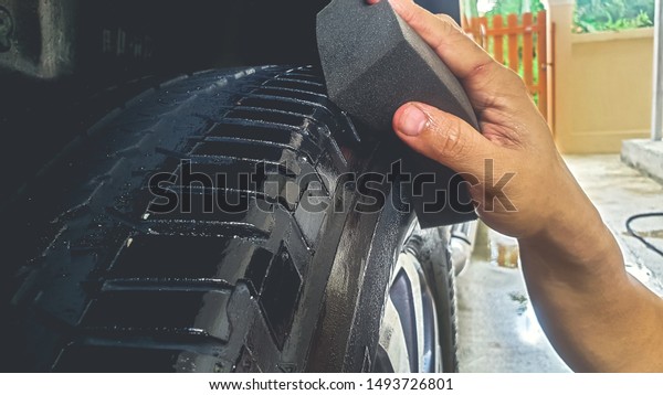Car Detailing process. Waxing black tire\
alloy wheel with sponge\
background.