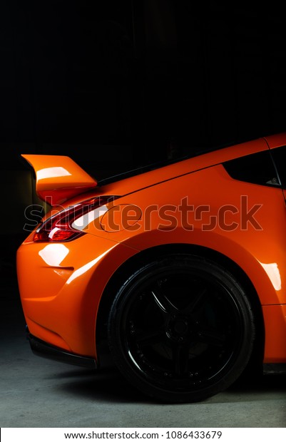 Car detailing series: Clean of rear orange sports\
car in the dark