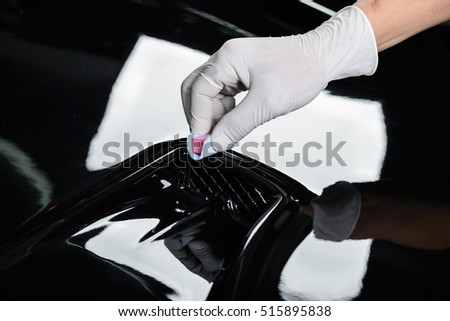 Car detailing series : Closeup of hand coating black car bonnet 