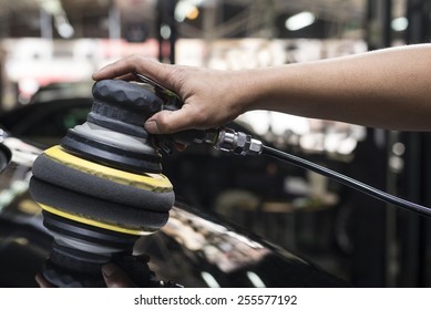 Car Detailing Series: Closeup Of Worker's Hand Using Tool Waxing Black Car Hood In Garage