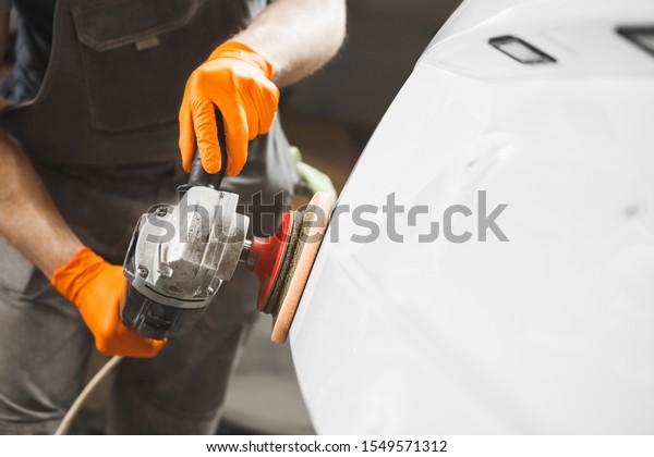 Car detailing series : man waxing auto in auto\
repair shop.