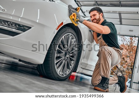 Car detailing series. Worker cleaning white car. Selective focus. Low angle view.