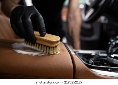 car detailing studio employee cleans the brown leather upholstery of a car  - Shutterstock ID 2193252129