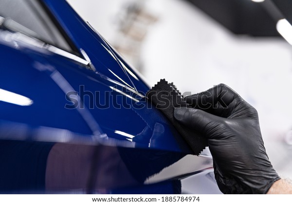 Car detailing studio worker applying ceramic coating\
on car