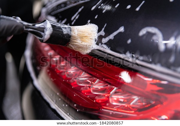 Car\
detailing studio worker cleaning car with\
brush
