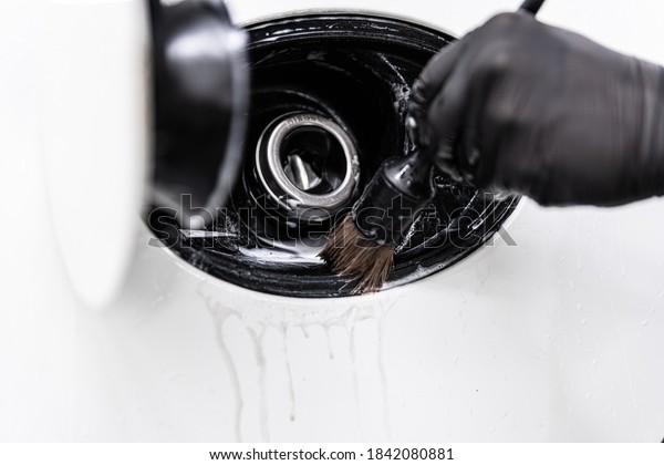 Car detailing studio worker cleaning fuel filler\
with a brush
