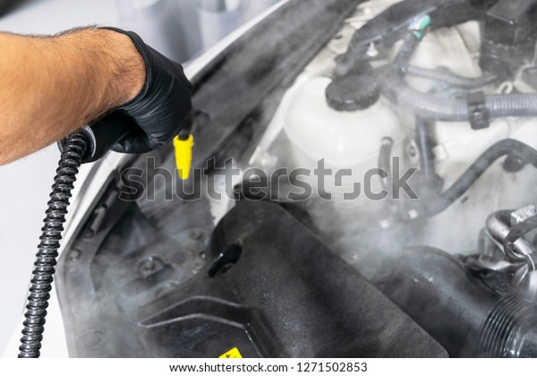 Car\
detailing. Car washing cleaning engine. Cleaning car engine using\
hot steam. Hot steam engine washing. Soft lighting. Car wash\
station worker cleaning vehicle. Vehicle wash\
concept