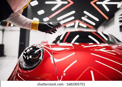 Car detailing - Worker checking car with lamp in auto repair shop. Car polishing. Selective focus.