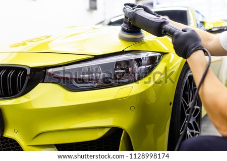 Car detailing - Worker with orbital polisher in auto repair shop. Selective focus. 