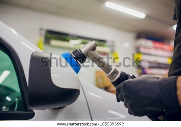 Car detailing - Worker\
with orbital polisher in auto repair shop. Car mirror polish.\
Selective focus.