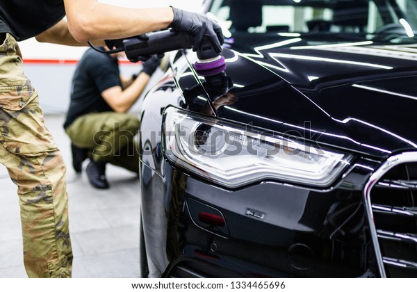 Car detailing - Worker with orbital polisher in auto
repair shop. 