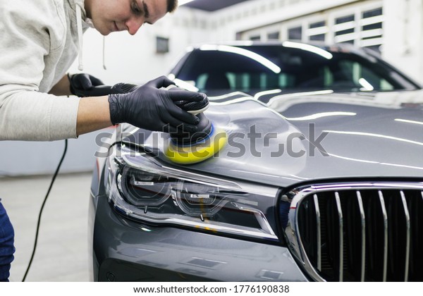 Car detailing - Worker with orbital polisher in auto\
repair shop. 