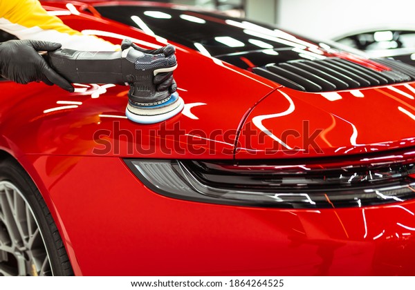 Car detailing - Worker with orbital\
polisher in auto repair shop. Selective\
focus.