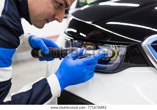 Car detailing - Worker with orbital polisher in auto\
repair shop. 